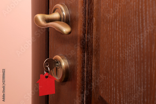 The concept of buying a home. Keys with keychain house in the door lock close-up