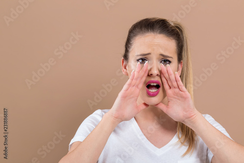 Young woman shouting on a brown background