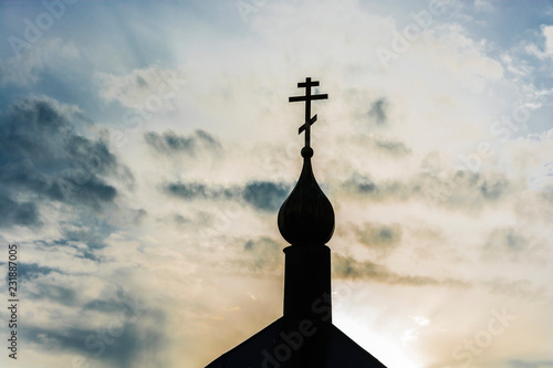 A small black church dome with a cross in backlight.