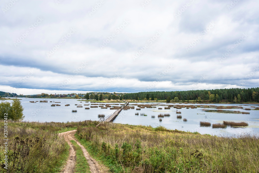 Autumn landscape with a long pedestrian bridge and a cloudy sky. Autumn landscape with a long pedestrian bridge and a cloudy sky.