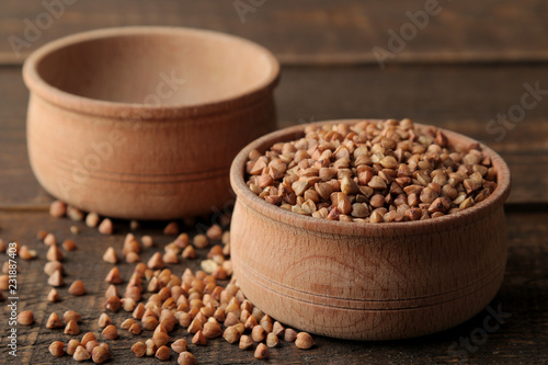 Dry buckwheat groats in a wooden bowl on a wooden brown table. cereals. healthy food. porridge. © MK studio
