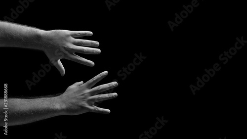 Male hands are trying to grab. Grabbing hands. Men's hands on a black background. Hands reach for the subject.