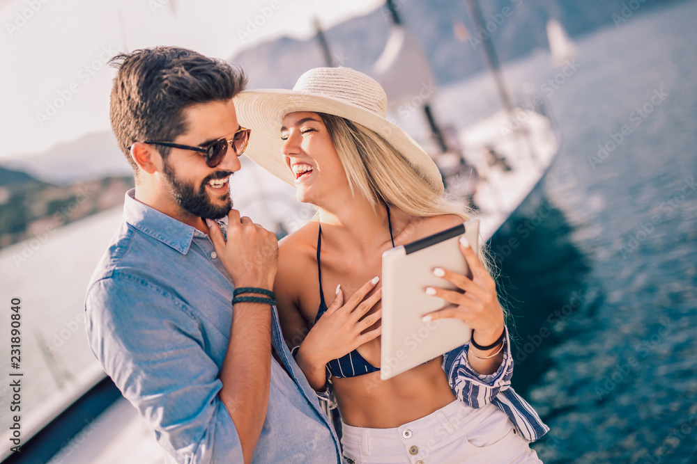 Couple in love, enjoying the summer time by the sea using digital tablet.