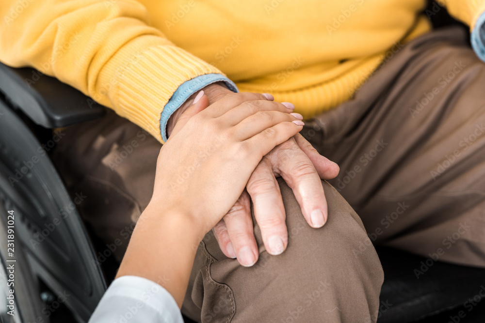 close up of female doctor holding disabled senior patient hand