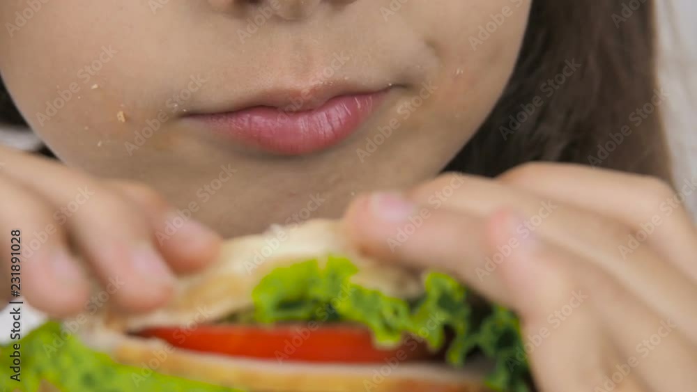 The child eats a hamburger. Close-up. The child eats a hamburger. Close-up.