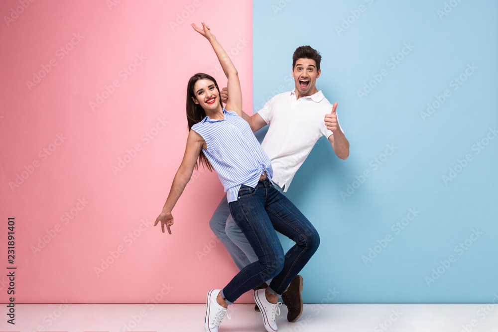 Full length image of optimistic man and woman in casual wear laughing and having fun together, isolated over colorful background - obrazy, fototapety, plakaty 
