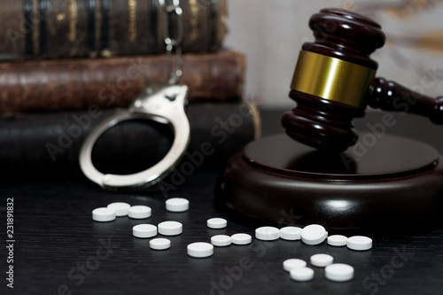 Judge's gavel with handcuffs, drugs on wooden table