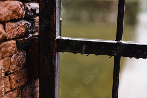 Rainy weather in autumn or summer, raindrops on a metal fence, protection of the house