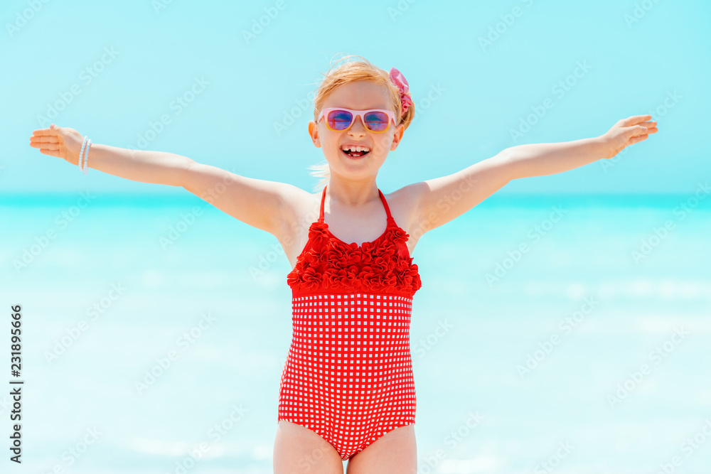 happy modern child in red swimsuit on seashore rejoicing happy modern child in red swimsuit on seashore rejoicing
