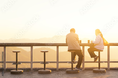 Carefree happy lover feeling happy and having coffee watching on top of mountain edge cliff enjoying sunlight .Enjoying nature sunset. Freedom. Enjoyment. Relaxing in mountains at sunrise. Sunshine. © photostriker