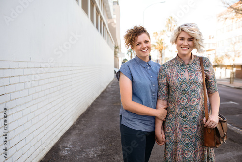 Affectionate young lesbian couple walking in the city holding hands