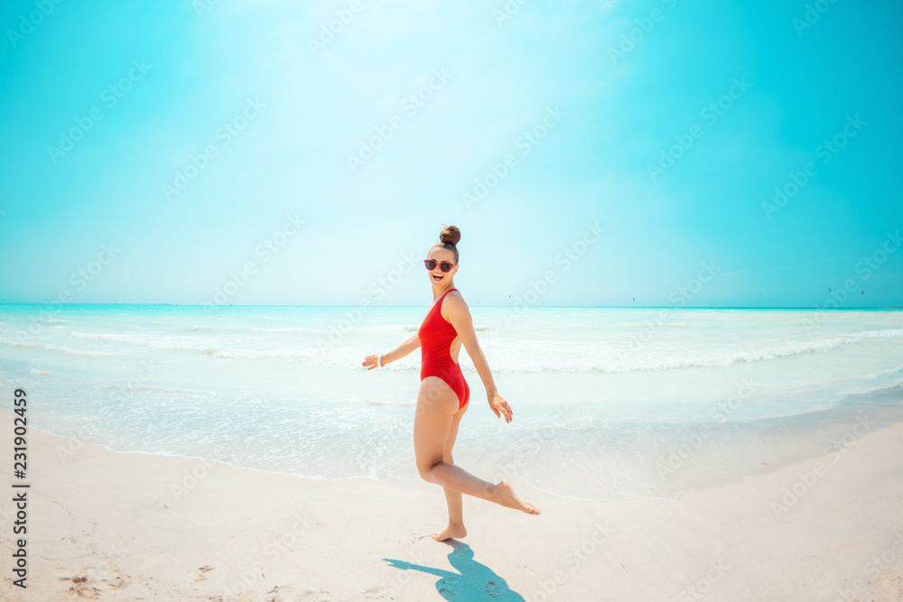 smiling young woman in red swimwear on beach having fun time