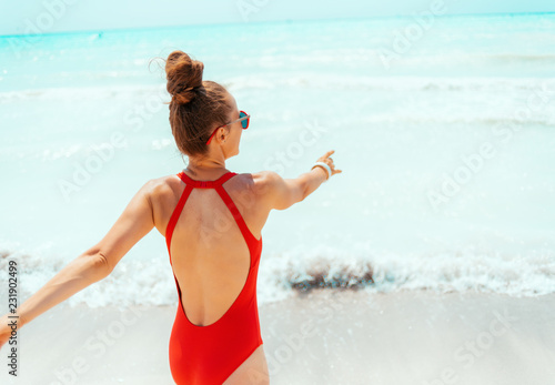 smiling young woman in red beachwear on beach having fun time