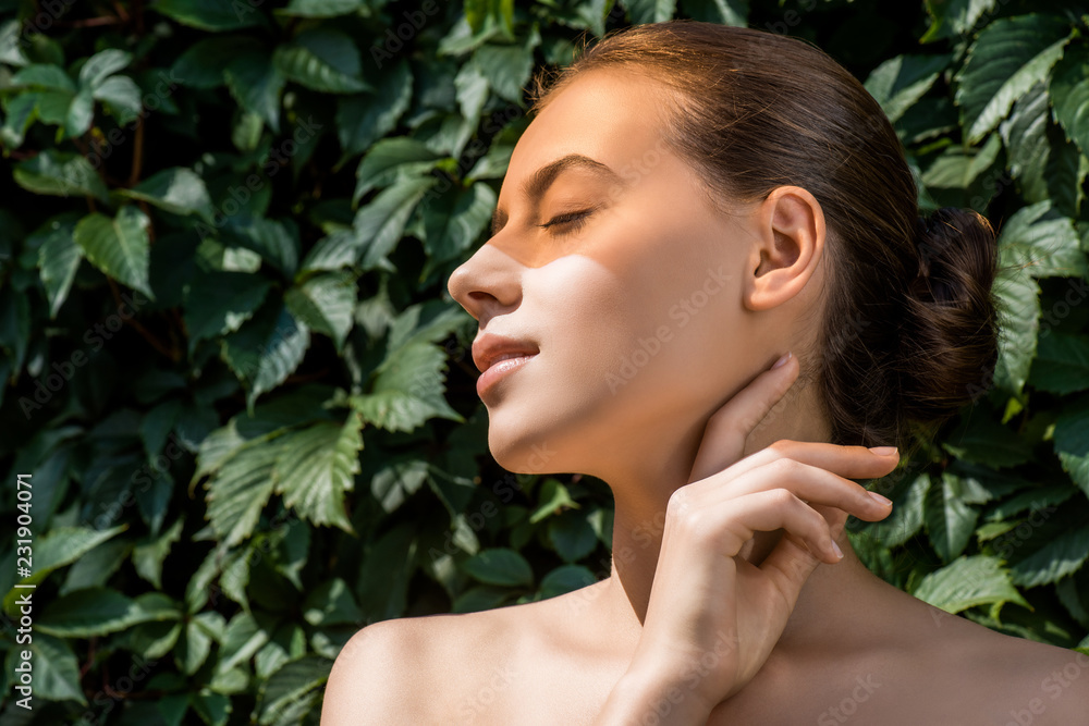 young woman with orange shadow on face and leaves at background