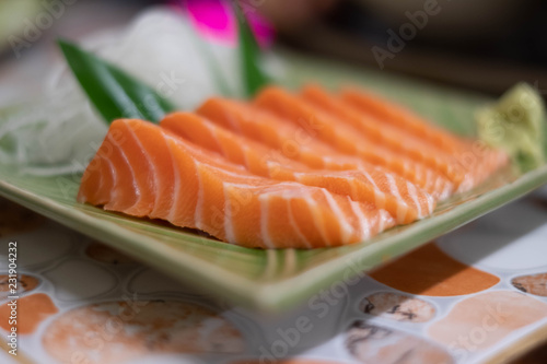 Close up of Salmon raw sashimi on green Japanese traditional dish on the table.