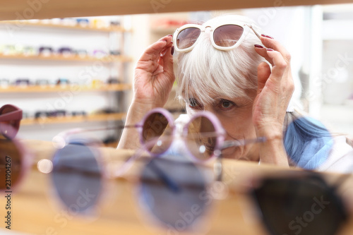 Okulary przeciwsłoneczne. Salon optyczny. Starsza kobieta kupuje okulary przeciwsłoneczne