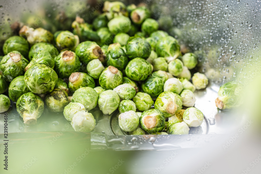 washing raw Brussels sprouts in kitchen sink washing raw Brussels sprouts in kitchen sink