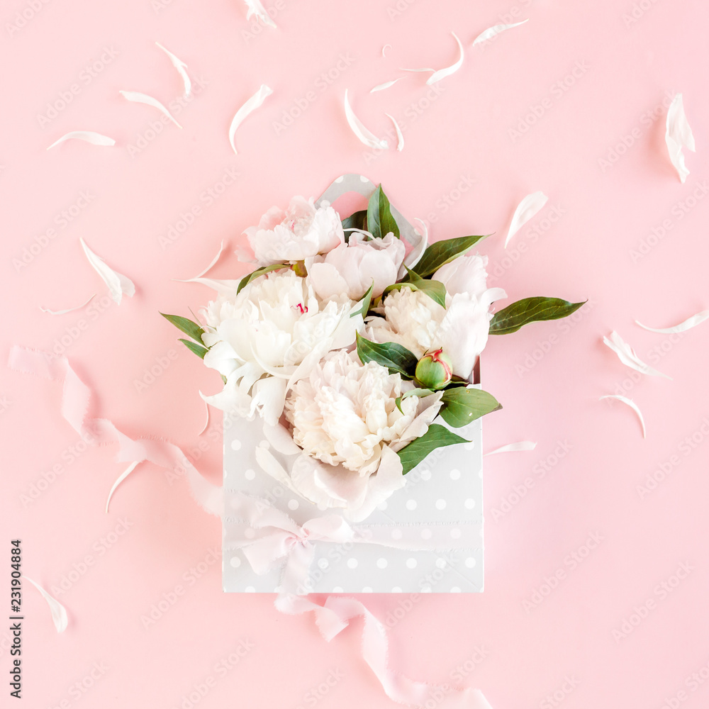 Beige bouquet of peonies in an envelope for flowers on pink background. Minimal floral concept greeting card. Flat lay, top view. 