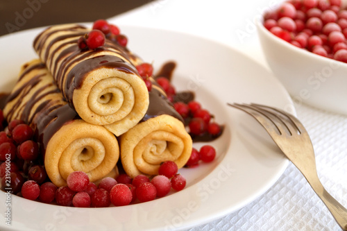 Homemade pancakes twisted with chocolate on a white plate.