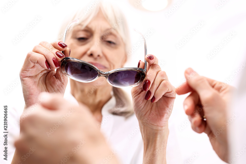 Ochrona oczu przed słońcem, okulary przeciwsłoneczne z filtrem.Starsza kobieta kupuje okulary przeciwsłoneczne - obrazy, fototapety, plakaty 