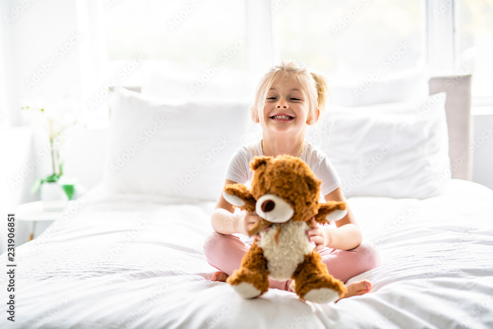 A Cheerful little girl in bed having fun A Cheerful little girl in bed having fun