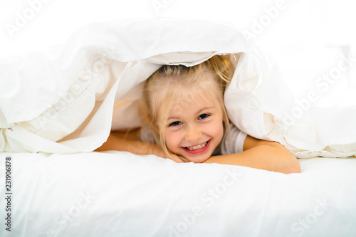 A Cheerful little girl in bed having fun