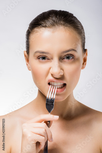 young beautiful woman holding silver fork near teeth