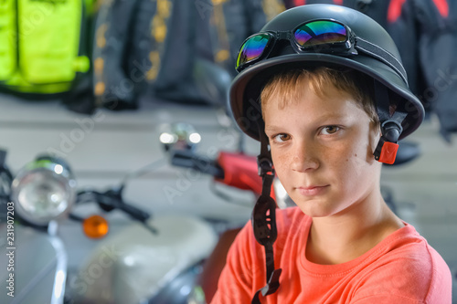 boy - teenager measures vintage motorcycle helmet  in a motorcycle store. portrait. close-up photo