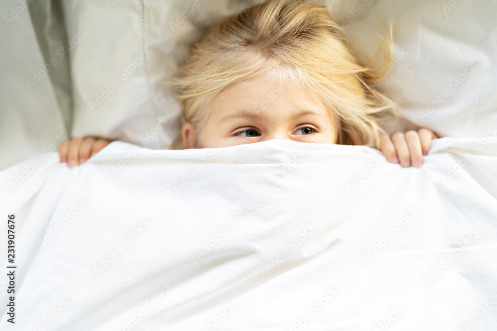 A little girl in bed below the covers A little girl in bed below the covers