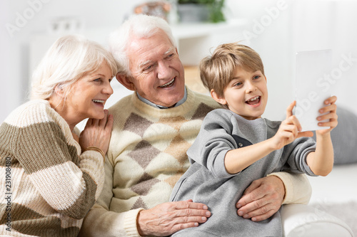 Smiling grandson taking selfie of himself and his happy grandparents photo