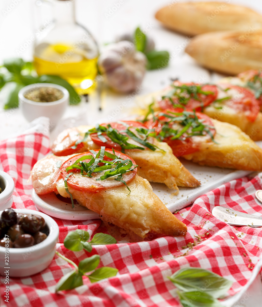Bruschetta, grilled slices of baguette with mozzarella cheese, tomatoes, garlic and aromatic basil on a white wooden table, close up. A delicious Mediterranean appetizer Bruschetta, grilled slices of baguette with mozzarella cheese, tomatoes, garlic and aromatic basil on a white wooden table, close up. A delicious Mediterranean appetizer
