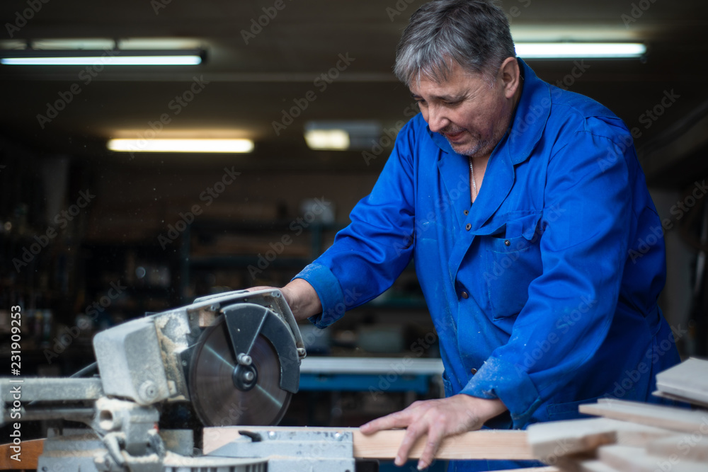 electric saw for sawing boards, the worker saws a wooden board in workshop electric saw for sawing boards, the worker saws a wooden board in workshop