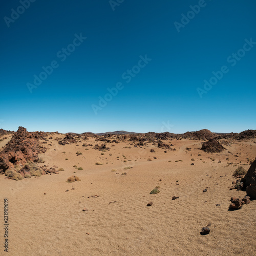 desert landscape with volcanic rocks and blue sky -