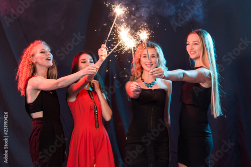 Celebrating with fun. Group of cheerful young women carrying sparklers. New year, holidays and party concept.