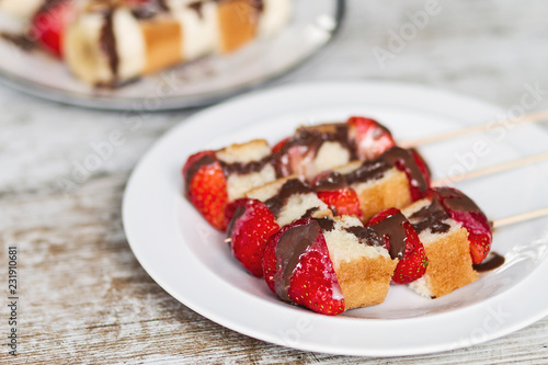 Fruit and cake skewers with melted chocolate