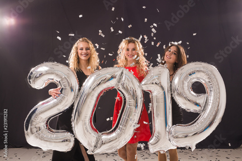 New Year party concept. Group of young women holding silver colored numbers 2019 and throwing confetti