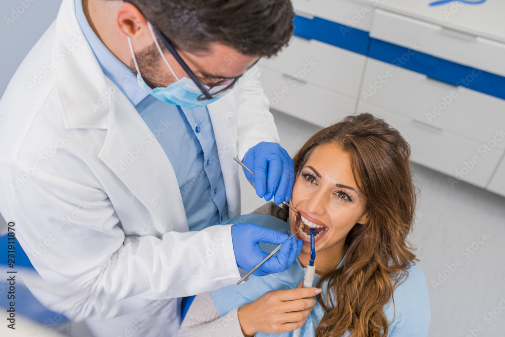 Professional handsome dentist examining teeth Professional handsome dentist examining teeth