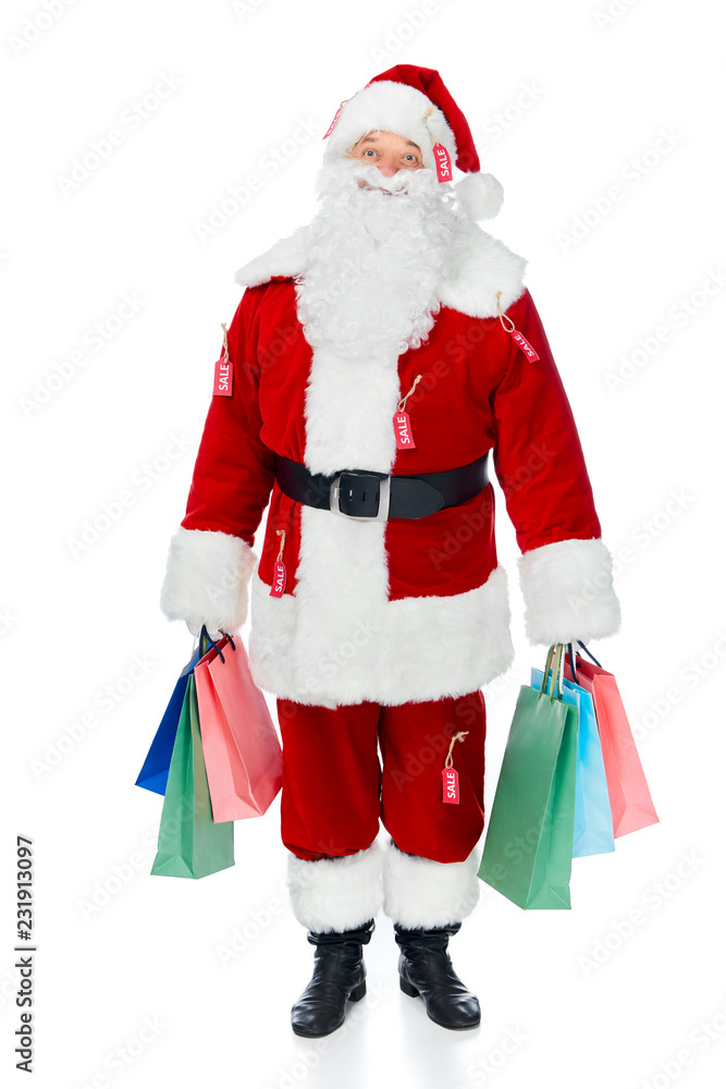 happy santa claus in red costume with sale tags holding shopping bags isolated on white happy santa claus in red costume with sale tags holding shopping bags isolated on white