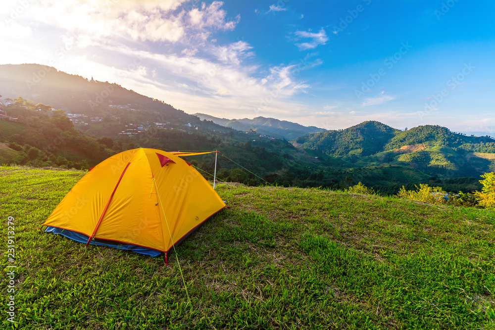 Camping orange tent on the mountain during sunrise in Chiang Rai, Thailand.