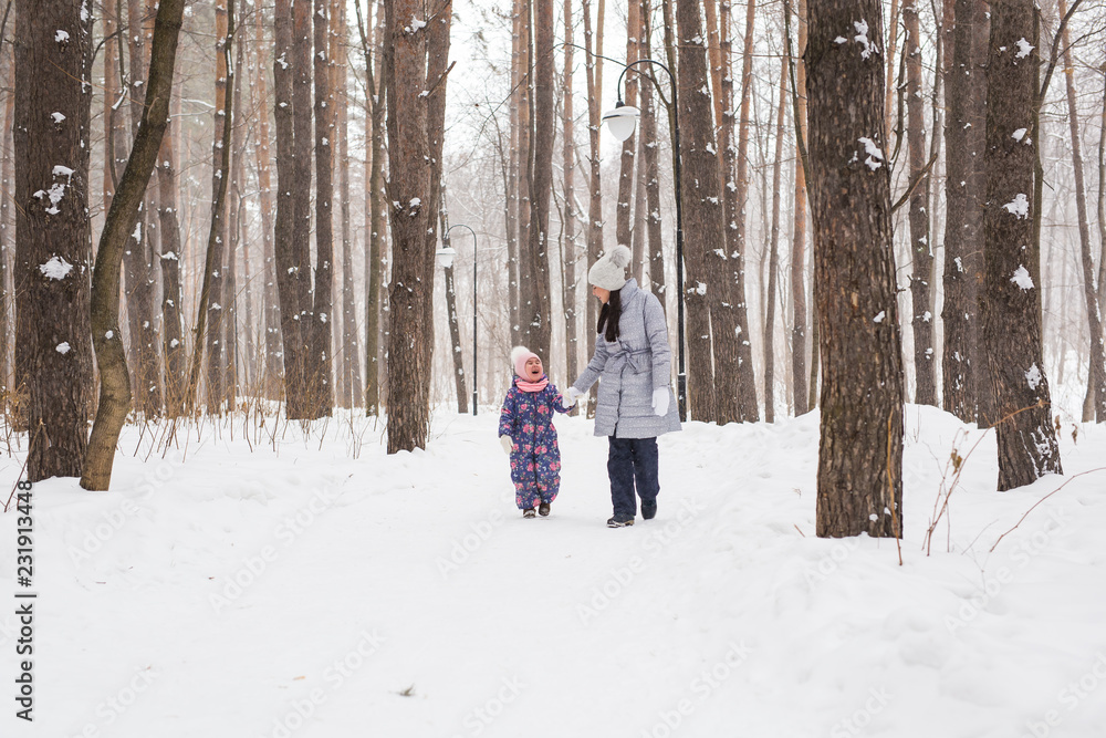 Fototapeta premium Motherhood, children and nature concept - Attractive young woman and adorable child walking in park