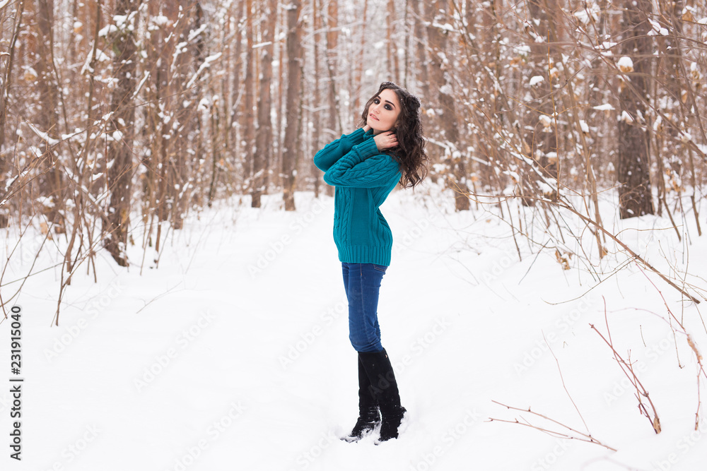 Beautiful young woman walking in the winter snowy nature