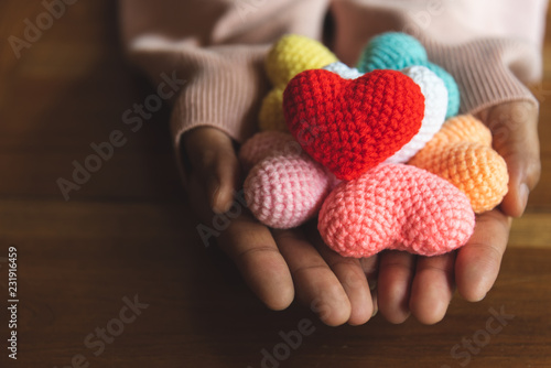 Mixed colors yarn heart on giving hands. Close up of colorful handmade. Heart donation concept. Valentine  love forever theme photo