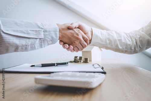 Real estate broker agent and customer shaking hands after signing contract documents for ownership realty purchase, Concept mortgage loan approval