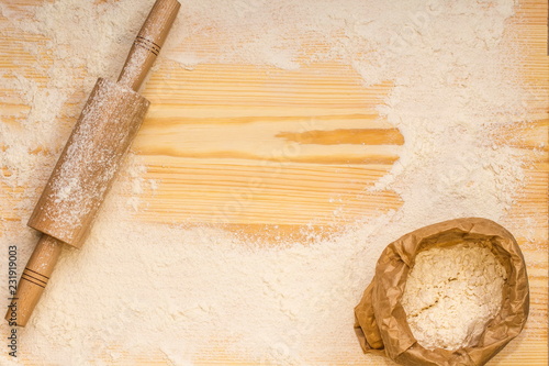 Flour and rolling-pin for dough on a wooden board. Baking background.