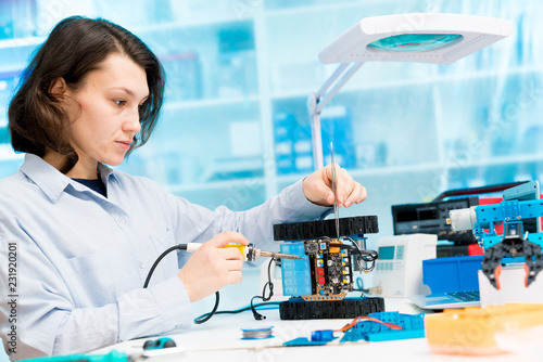 Student girl in electronics laboratory, experiment with microcontroller and robot cnc module