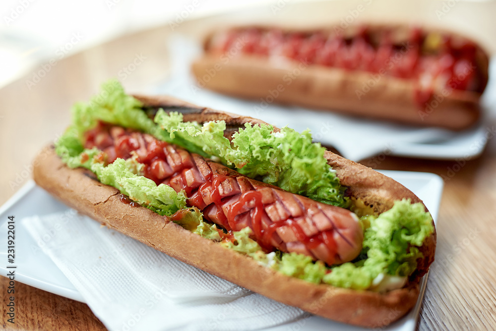 Delicious hot dogs in a fresh bun with ketchup and mustard and lettuce Delicious hot dogs in a fresh bun with ketchup and mustard and lettuce