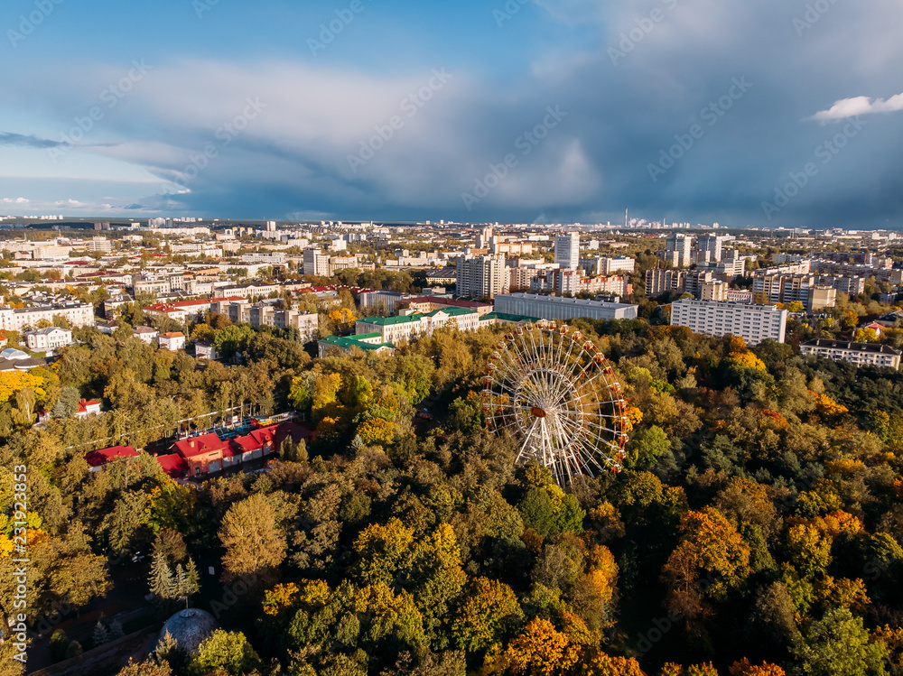 Ferris wheel amusement Park, shrouded in autumn mood yellowed trees. Aerial drone. Minsk, Republic Belarus