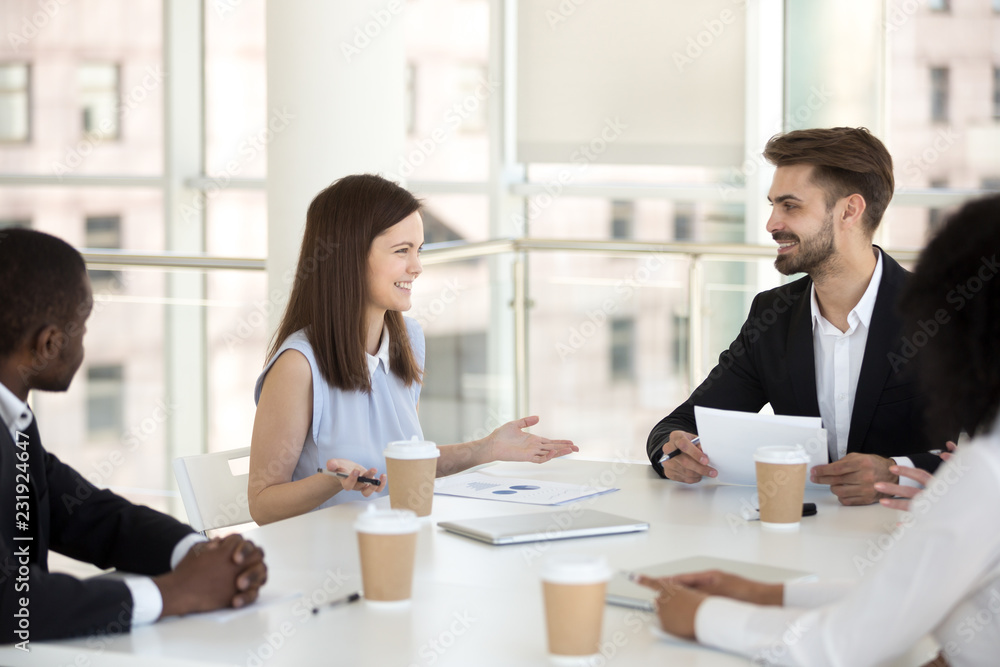 Millennial workers sit at table in boardroom having friendly talk during briefing, smiling young employees laugh negotiating or brainstorming in office, coworkers have casual discussion at meeting Millennial workers sit at table in boardroom having friendly talk during briefing, smiling young employees laugh negotiating or brainstorming in office, coworkers have casual discussion at meeting