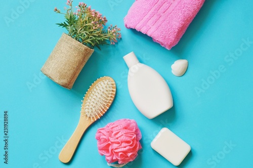 Flat lay bath products, bathroom stuff. Flowers, pink towel, shampoo bottle, soap, sponge and hair brush photo