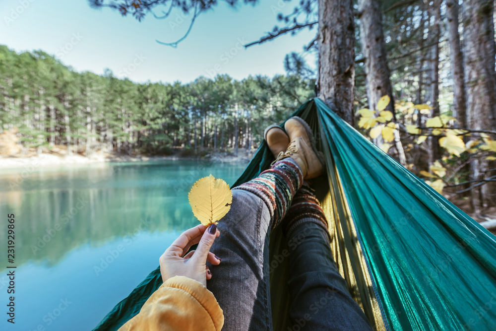 Woman relaxing in the hammock by the lake - obrazy, fototapety, plakaty 